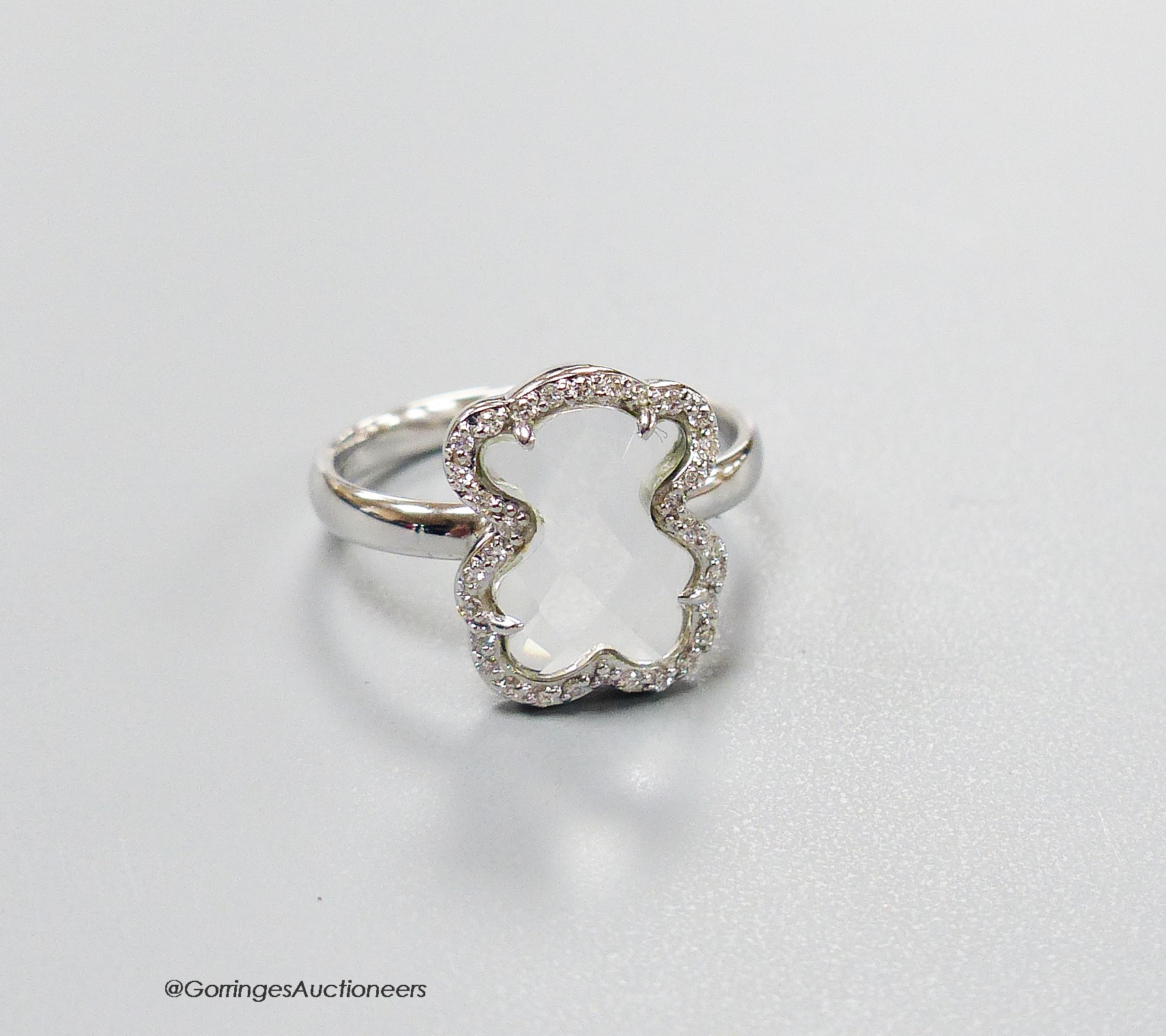 A modern Tous 750 white metal and facetted rock crystal dress ring, with diamond chip set border, size J, gross weight 3 grams.